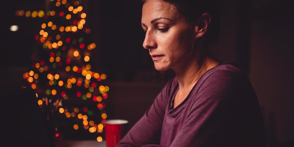 Sad woman sitting in front of a Christmas tree