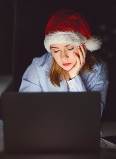 Sad woman in santa hat sitting in front of laptop