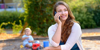 Woman on phone with baby playing in background