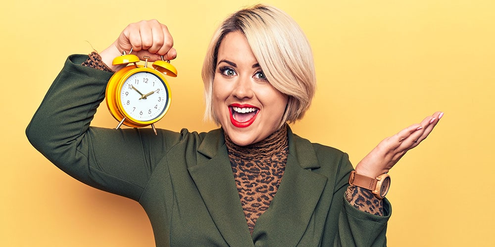 Smiling blonde woman holding clock