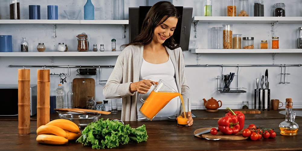 Pregnant woman with orange juice and vegetables