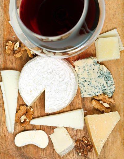 A glass of wine and assortment of soft cheeses