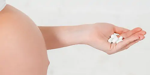 Pregnant woman holding a handful of pills