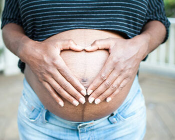 Woman holding hands in heart-shape over pregnant stomach