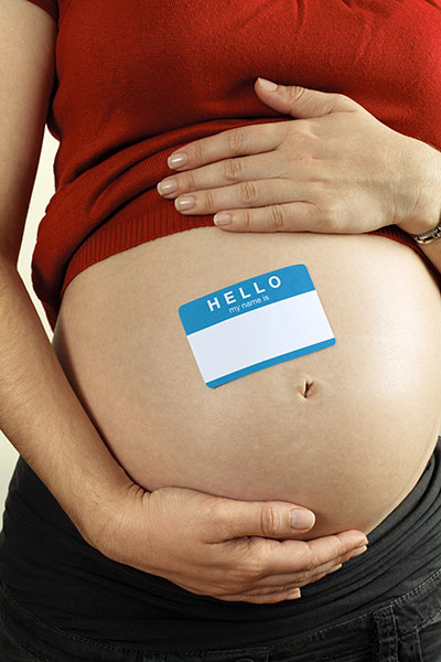 Pregnant woman with blank "hello my name is" sticker on stomach