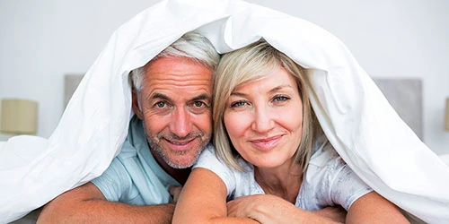 Middle-aged couple under blankets