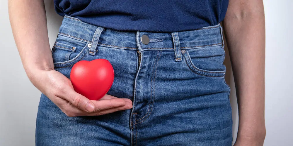 Woman holding heart near pelvis