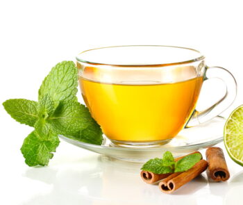 A cup of green tea with mint leaves and cinnamon sticks.