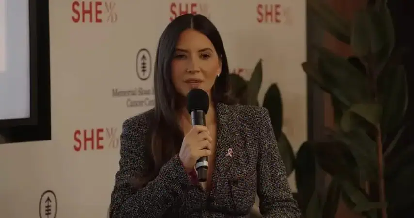Dr. Thais Aliabadi speaking at women's health event, holding a microphone.