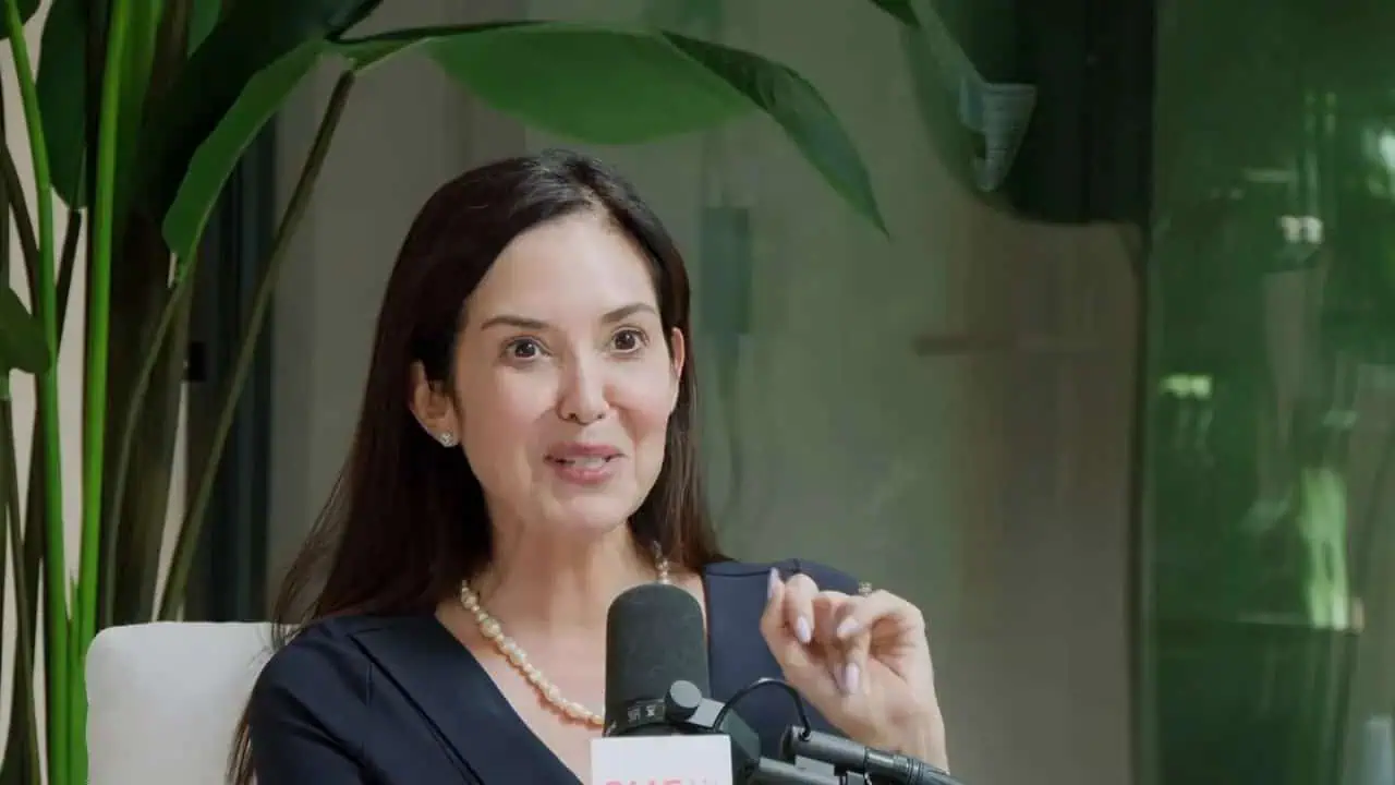 Dr. Thais Aliabadi MD speaking at a medical event, holding a microphone.