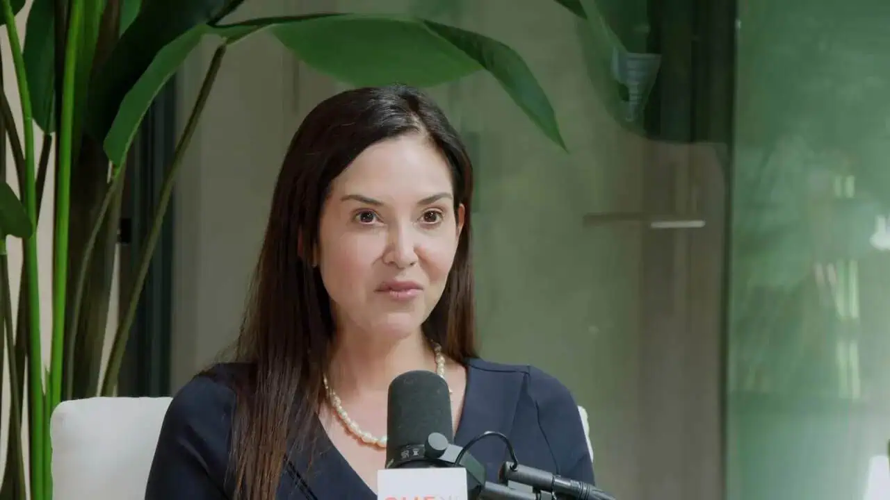 Thais Aliabadi MD speaking at a professional event with a microphone.