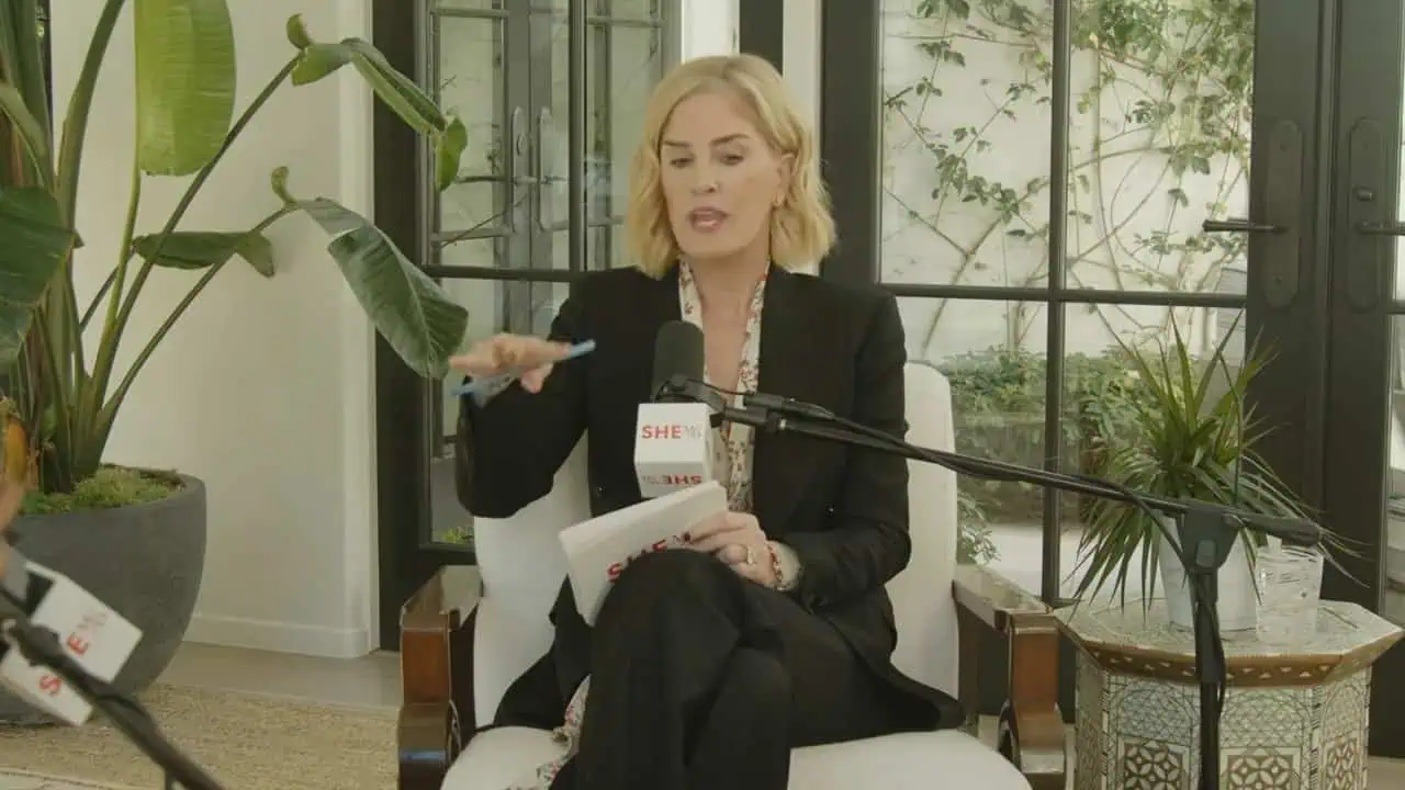 Emma Grede gesturing during an interview with microphone and studio plants