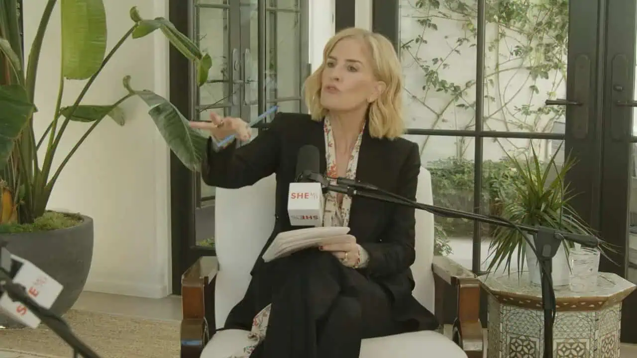 Emma Grede speaking confidently during the interview with plants and studio backdrop