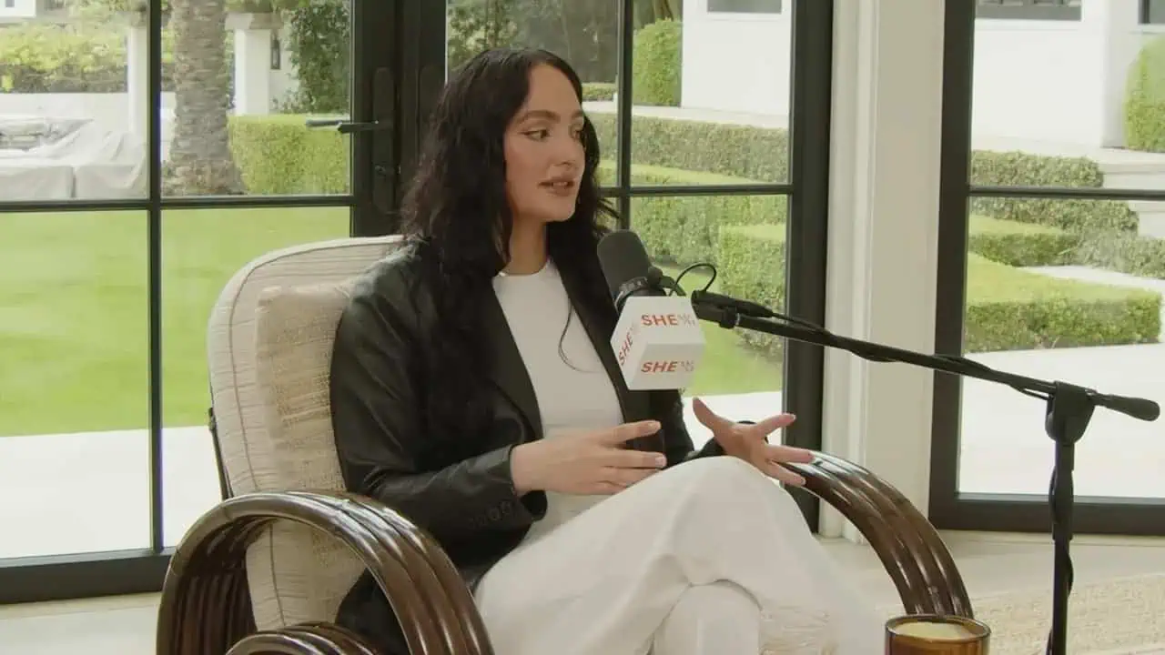 Dr. Thais Aliabadi MD speaking into a microphone in a professional setting.
