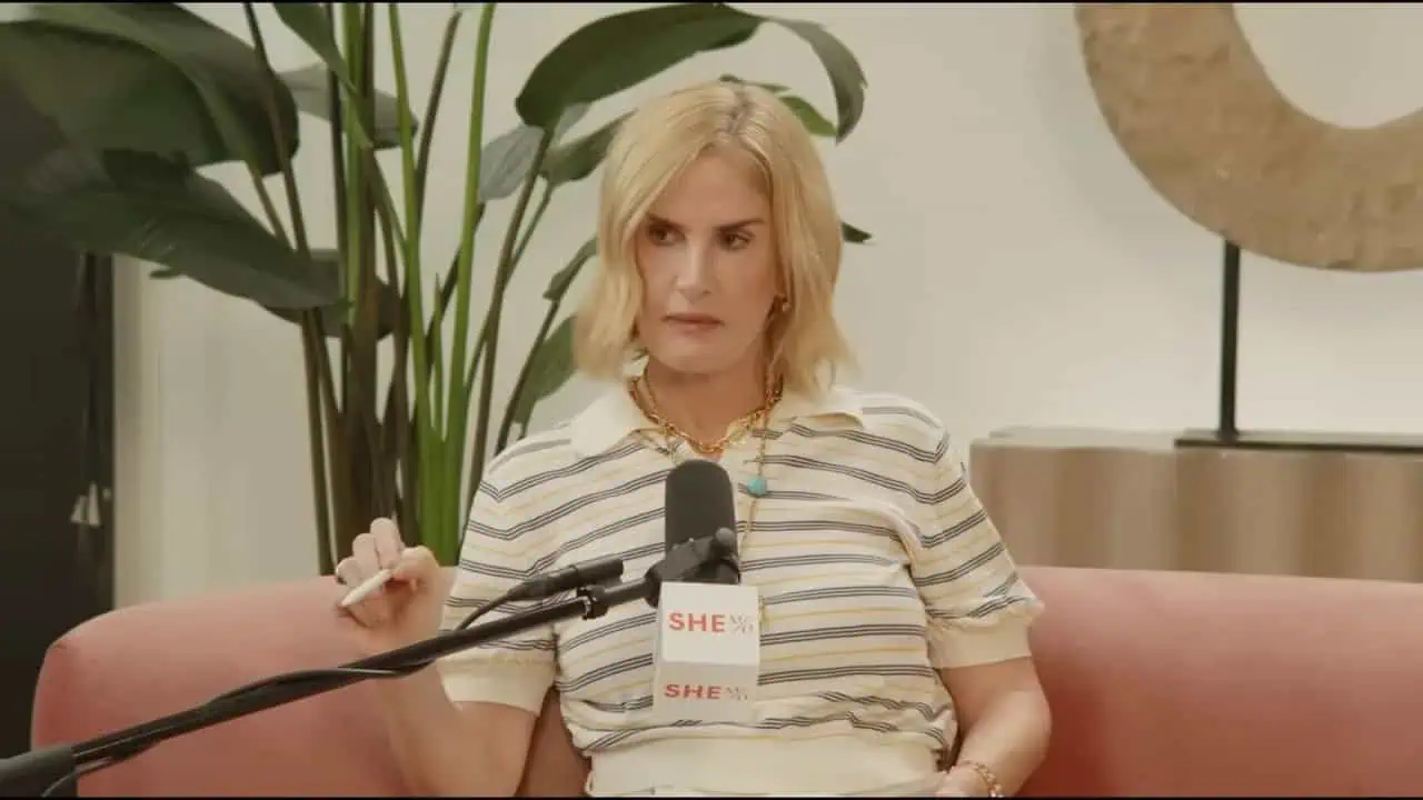 Thais Aliabadi MD during a medical interview, sitting on a pink sofa with a microphone.