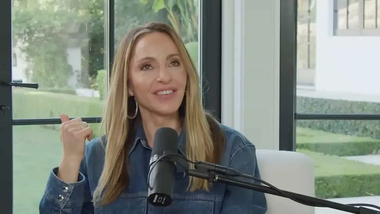 Thais Aliabadi MD speaking into microphone in a modern clinic setting.