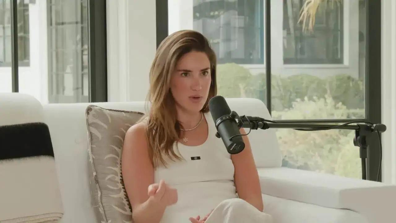 Tinx speaking into microphone while seated on white chair