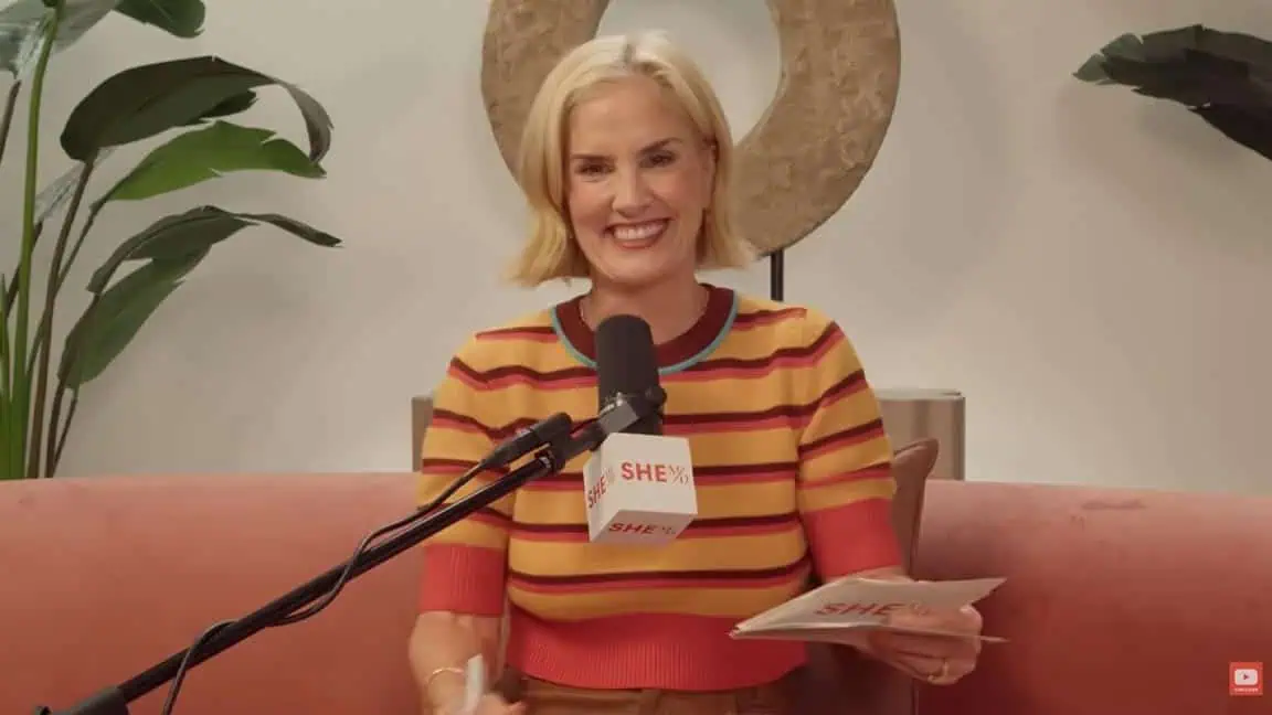 Thais Aliabadi MD smiling during a presentation with a microphone and notes.