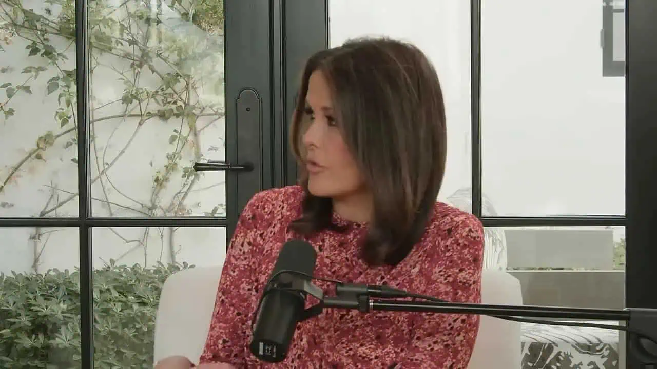 Dr. Thais Aliabadi wearing a red floral blouse, speaking into a microphone.
