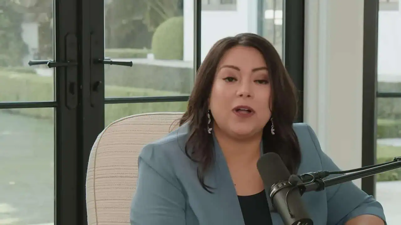 Thais Aliabadi MD speaking during a podcast interview in a modern office setting.
