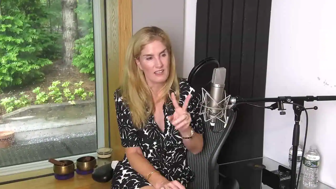 Thais Aliabadi MD speaking into microphone in recording studio.