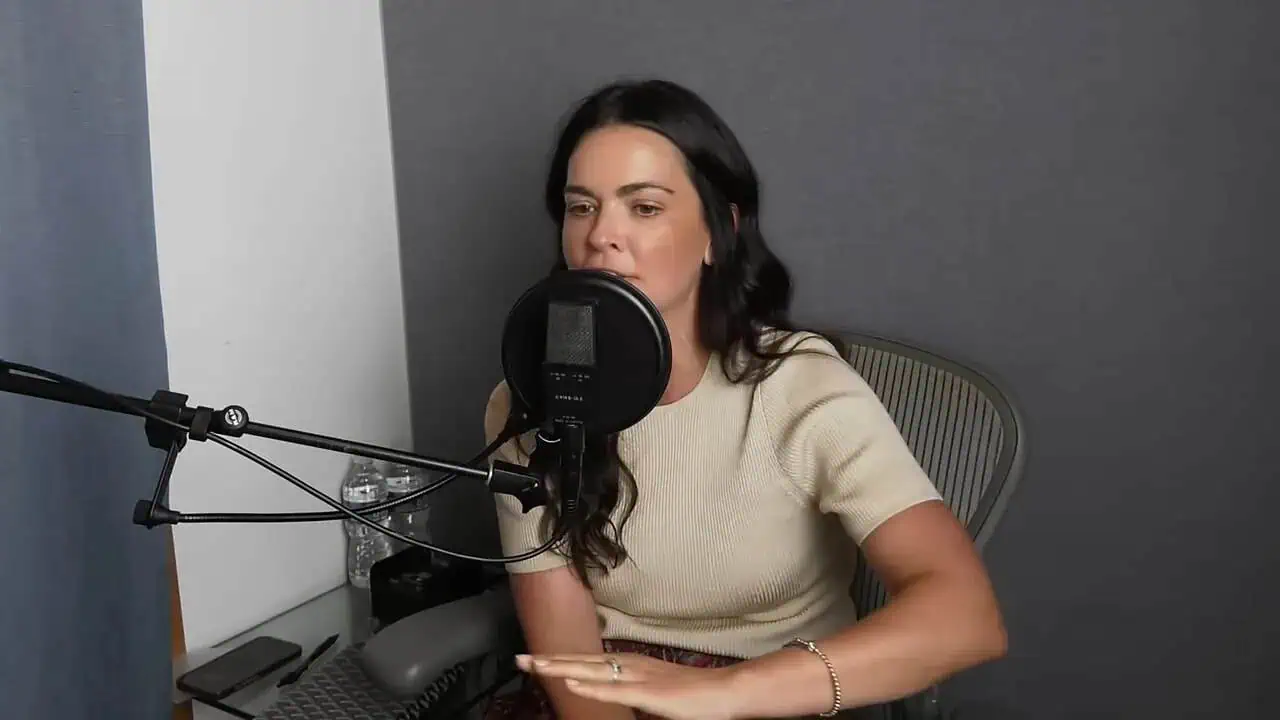 Thais Aliabadi MD speaking into microphone in recording studio.