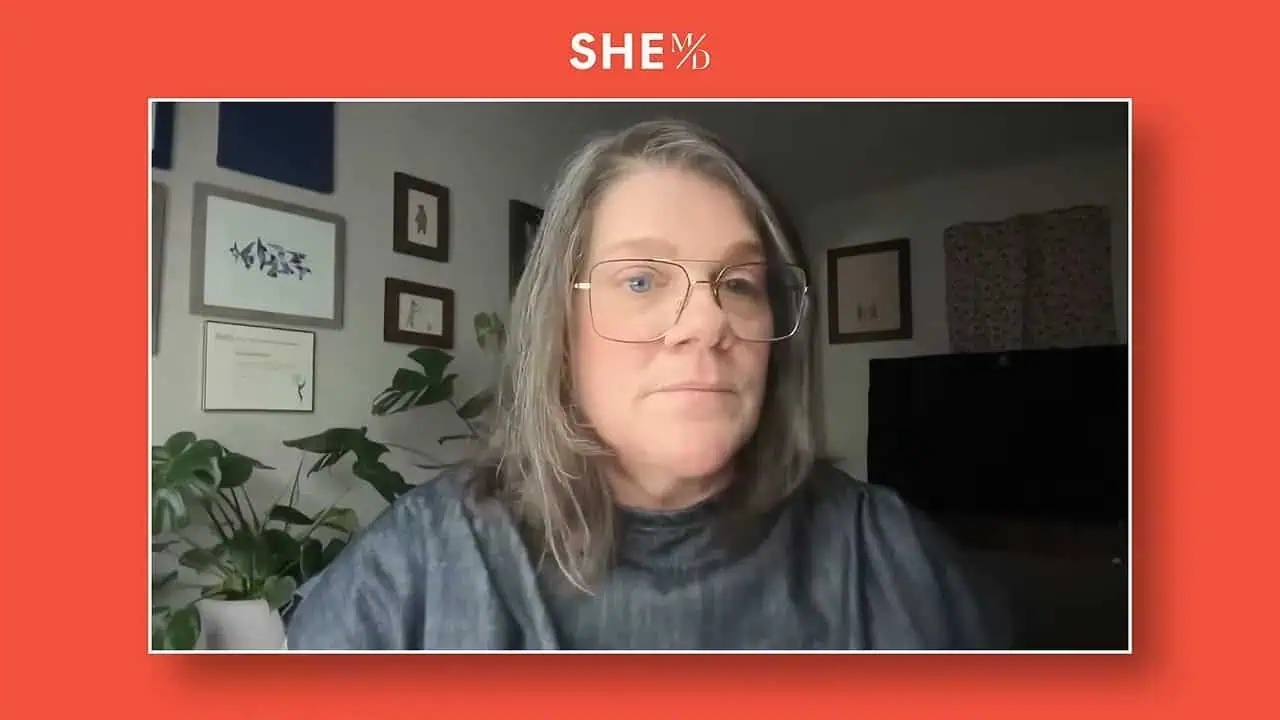 Ami Armstrong speaking in a framed video call with red SHE MD background