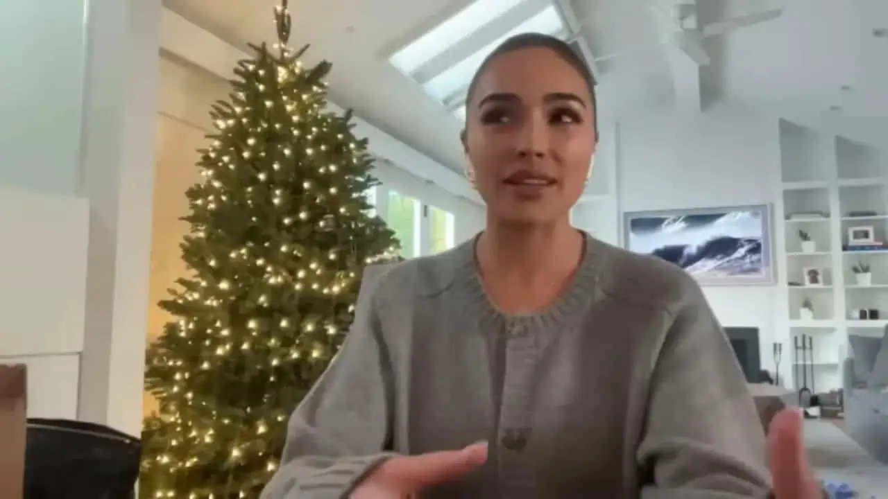 Olivia Culpo speaking from a room with a decorated Christmas tree