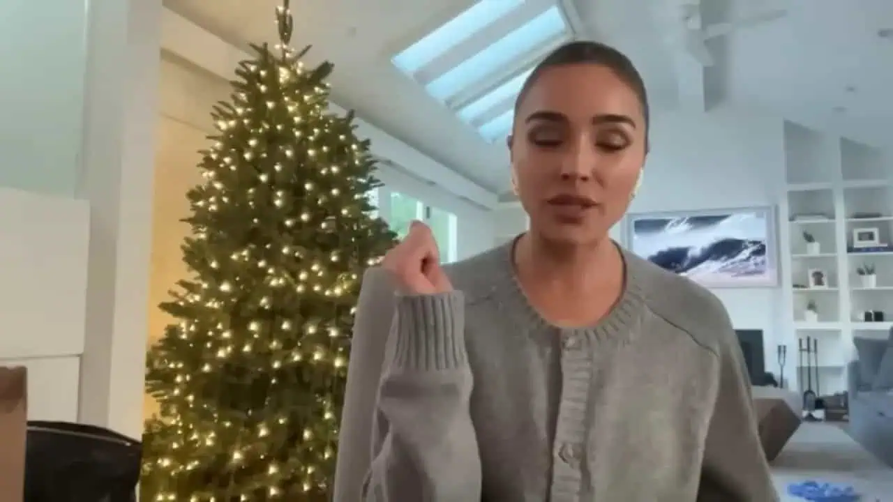 Olivia Culpo speaking with a Christmas tree behind her