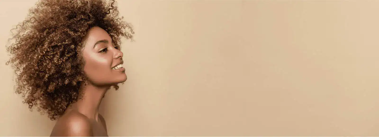Portrait of Thais Aliabadi MD with natural curly hair against a beige background.