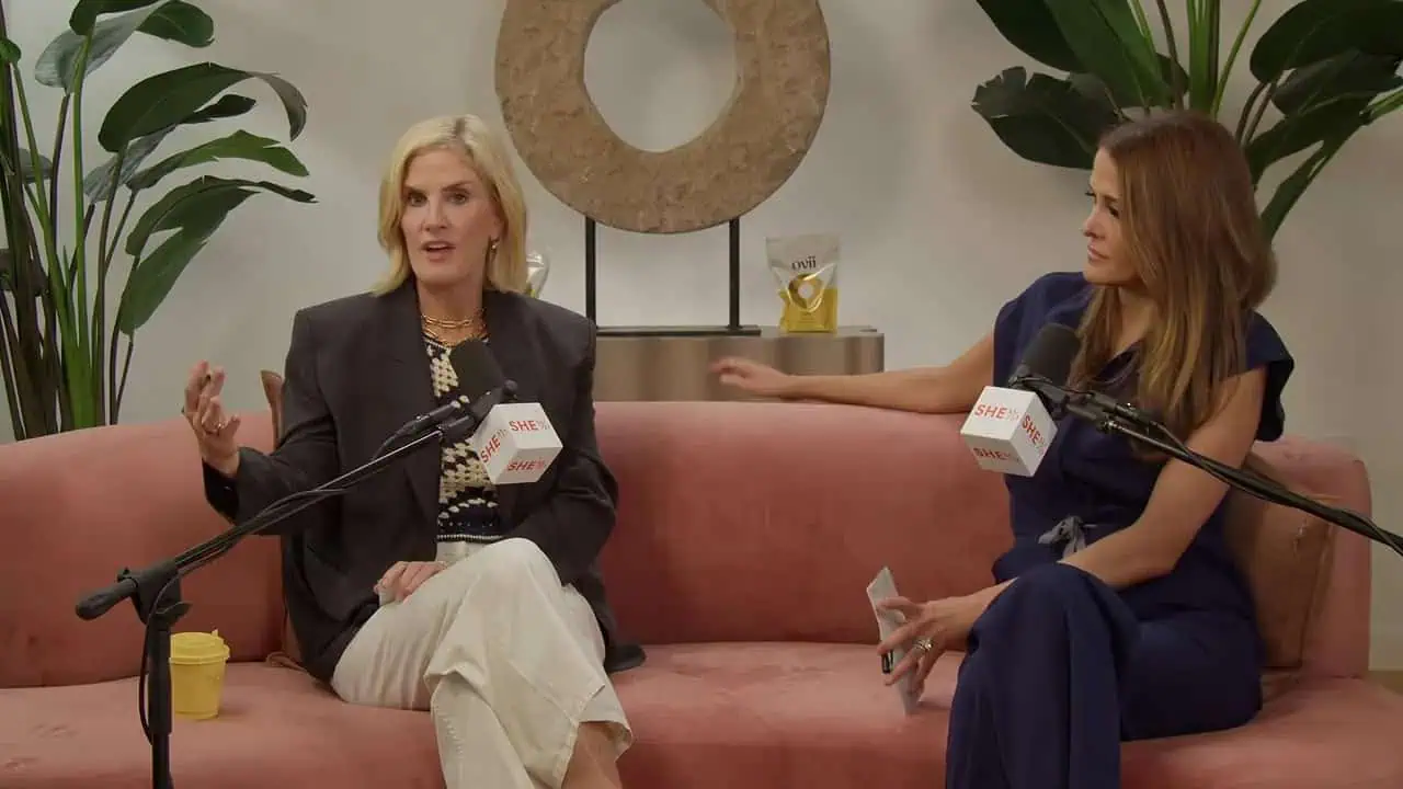 Whitney Cummings and Dr. Aliabadi seated together on a pink sofa with microphones
