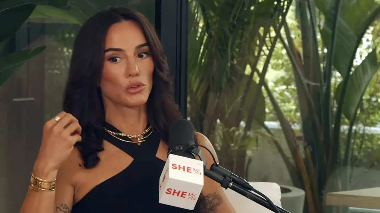Senada Greca speaking into a microphone during a discussion about strength and health