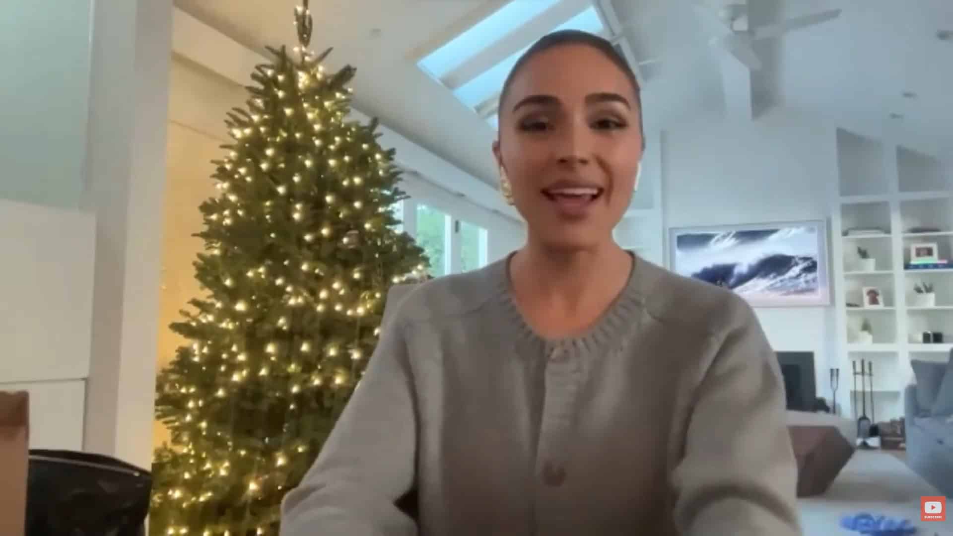 Thais Aliabadi MD smiling in a modern, well-lit office with a Christmas tree.