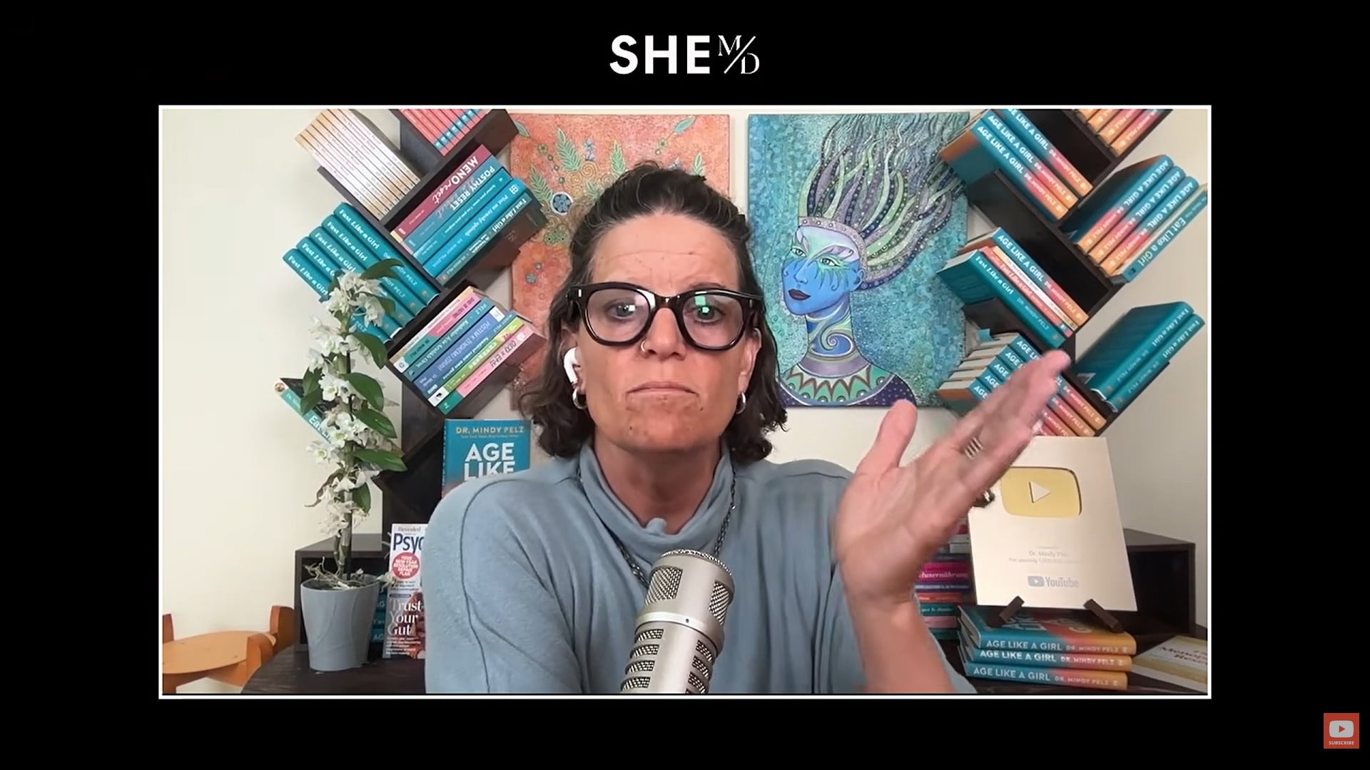 THAIS ALIABADI MD speaking in a studio with books and artwork in the background.