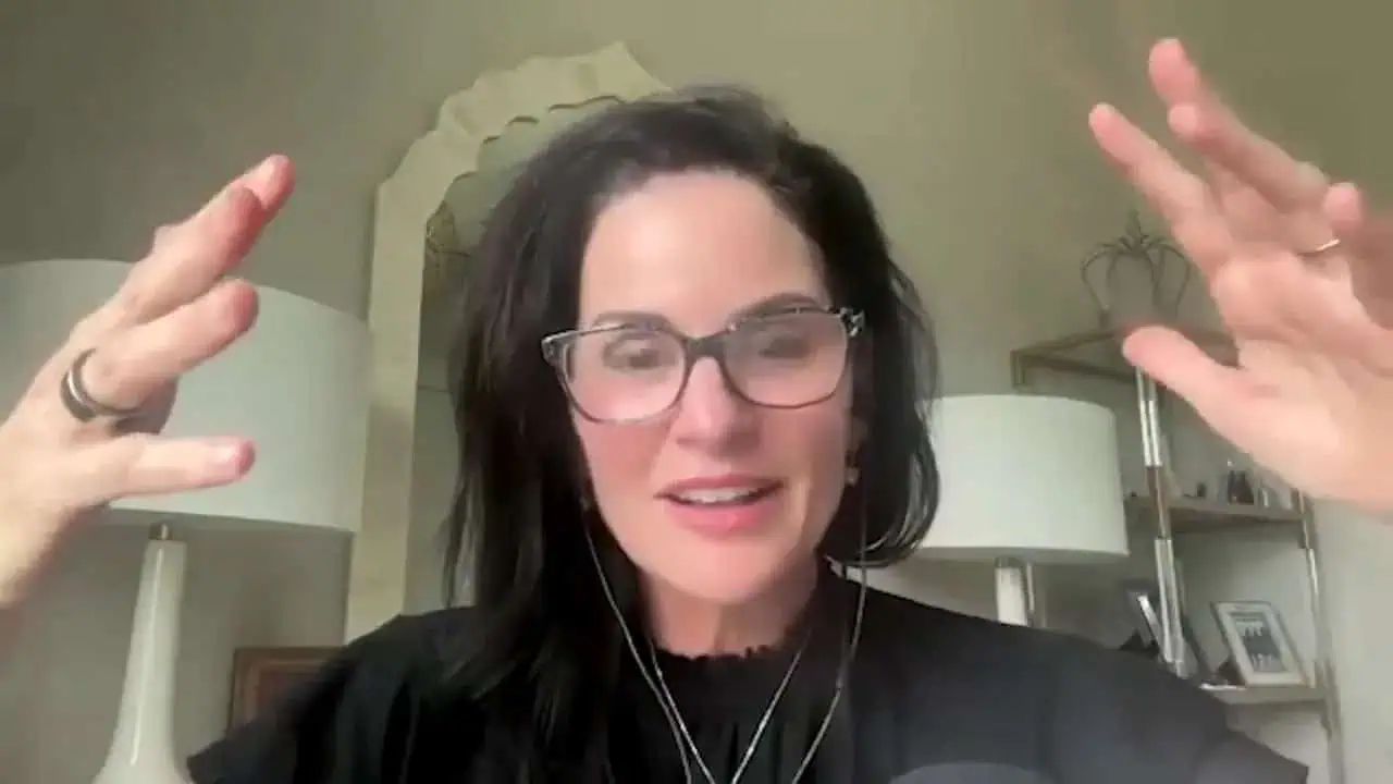 Thais Aliabadi MD smiling, wearing glasses, in a professional setting.