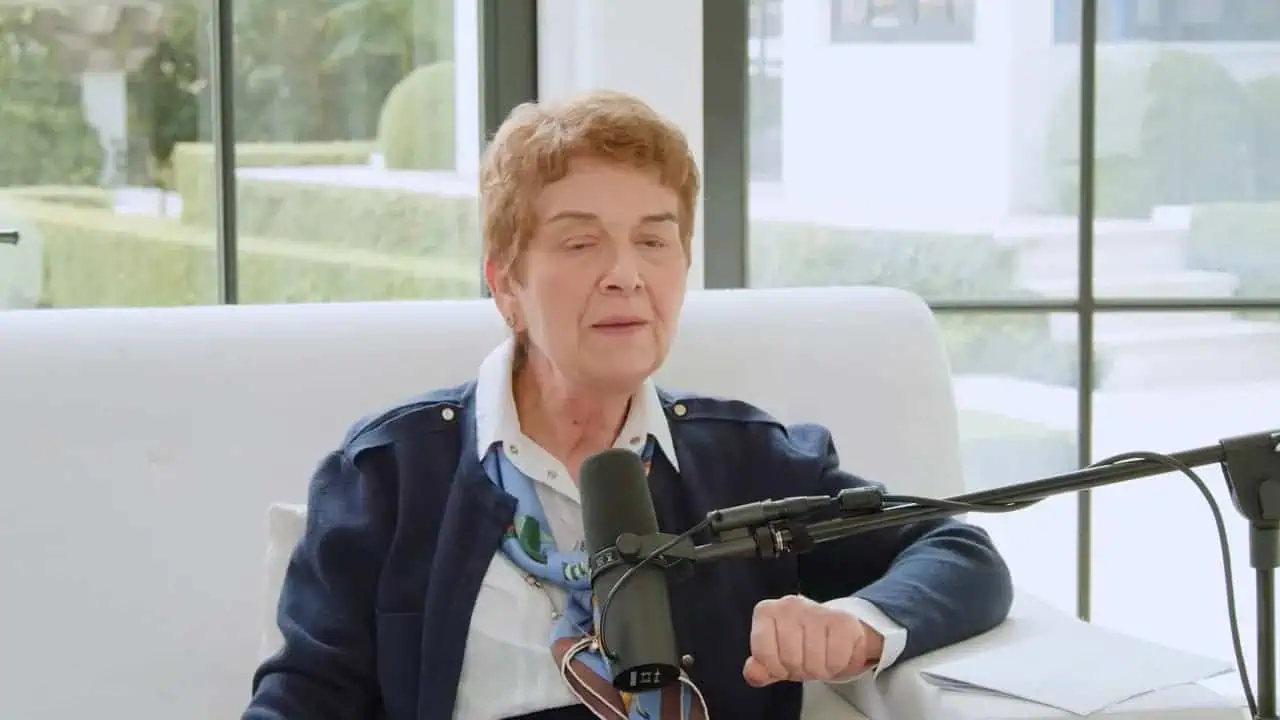 Thais Aliabadi MD in a professional setting with microphone and documents.