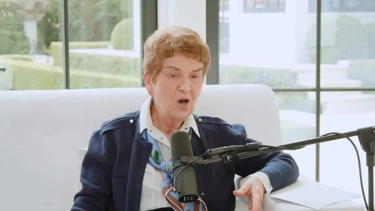 Thais Aliabadi MD speaking into a microphone in a modern clinic setting.