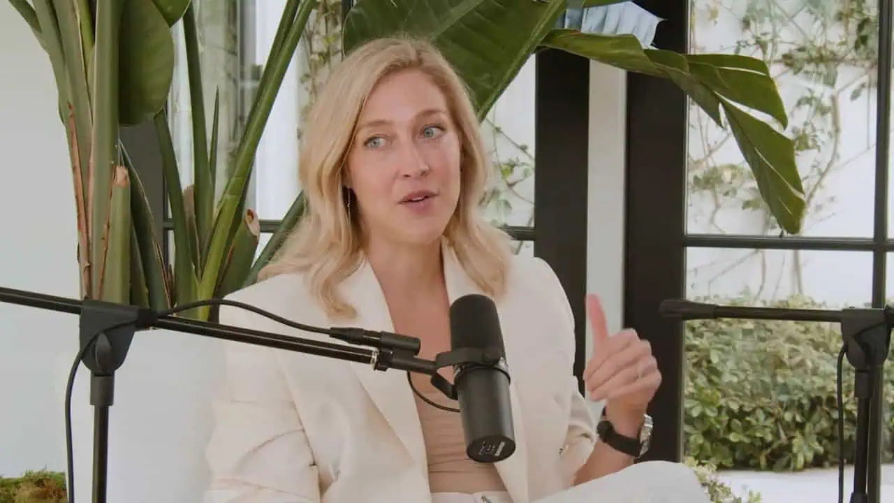 Sarah Wragge seated with a microphone in front of tall green plants