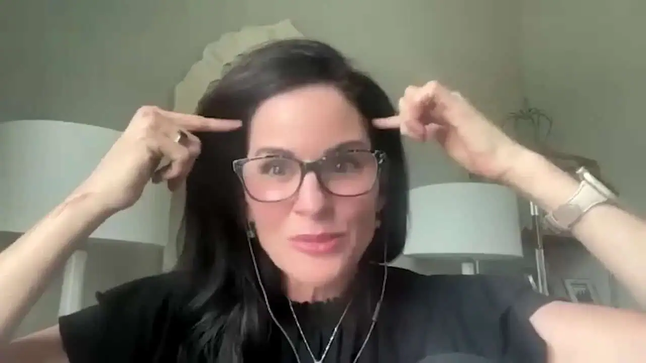 Dr. Haver pointing with both hands toward her temples